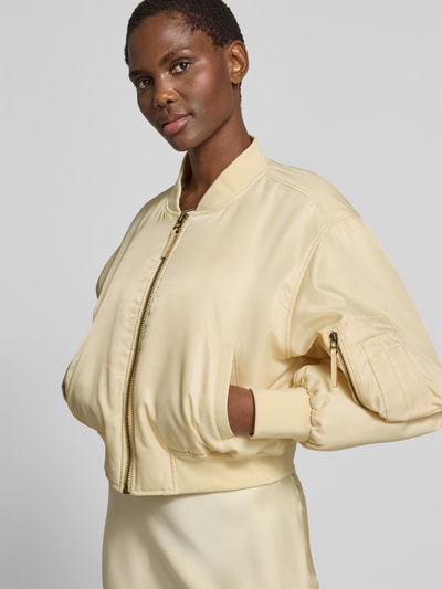 Frauenmodel trägt Bomberjacke mit Stehkragen von Anine Bing in Creme, Regular-Fit, Reißverschluss, Eingrifftaschen, elastische Abschlüsse, Nahaufnahme Oberkörper. Rückenlänge 50 cm, Brustweite 60 cm, Ärmellänge 58 cm.