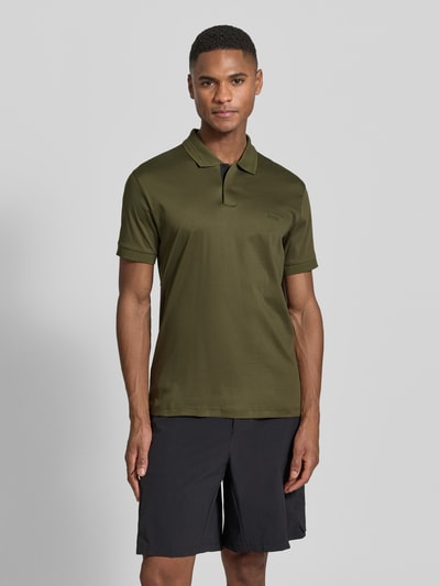 Männermodel trägt Regular Fit Poloshirt aus reiner Baumwolle Modell 'PS Spirit 70 Plk' von BOSS Green X PORSCHE, unifarben, Ganzkörperansicht von vorne.