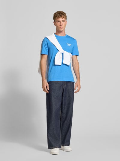 Männermodel trägt Regular Fit T-Shirt aus reiner Baumwolle Modell 'Nesptee' von HUGO Blue, leuchtend blau, weiße Akzente, Ganzkörperansicht von vorne.