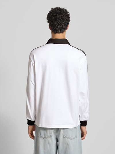 Männermodel trägt Regular Fit Longsleeve mit Logo-Stitching von adidas Originals, Baumwolle, weiße Farbe mit schwarzen Details, Ganzkörperansicht Rückansicht.