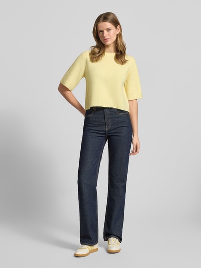 Frauenmodel trägt Boxy Fit T-Shirt aus Rippstrick mit Woll-Anteil Modell 'SILLY' von Pieces, Optik: Unifarben, Passform: Boxy-Fit, Rundhals, Kurzarm, Materialverarbeitung: Rippstrick, sanft gelbe Farbe, glatte Textur, Ganzkörperansicht von vorne.