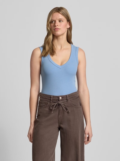 Kobiece modelka nosi Slim Fit Top mit V-Ausschnitt von Gina Tricot, elastyczna mieszanka bawełny, krój slim fit, dekolt w serek, krój bez rękawów, długość tyłu w rozmiarze S: 52 cm, niebieski top, brązowe spodnie, gładkie tkaniny, widok całej sylwetki od przodu.
