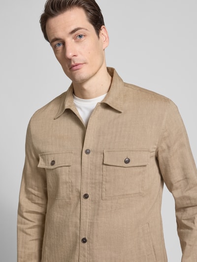 Männermodel trägt Regular Fit Hemdjacke mit Eingrifftaschen von Tiger Of Sweden aus reiner Baumwolle in Beige, Nahaufnahme Oberkörper.