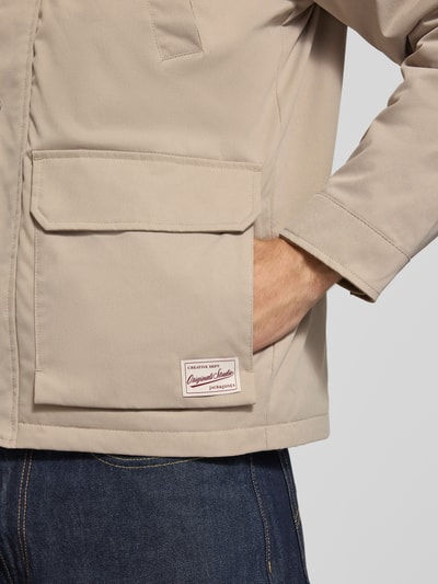 Männermodel trägt Regular Fit Jacke in Stiksels van JACK & JONES met opgestikte zakken en logopatch, detailaufnahme rechterzij. Ruglengte maat M: 72 cm, schouderbreedte: 49 cm, borstwijdte: 59 cm, mouwlengte: 65 cm.