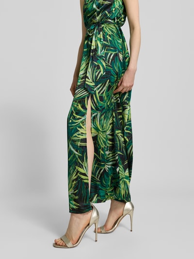 Frauenmodel trägt Maxikleid mit Bindegürtel von Apricot in Grün mit tropischem Allover-Muster, Material-Mix, A-Linie, Nahaufnahme Unterkörper.