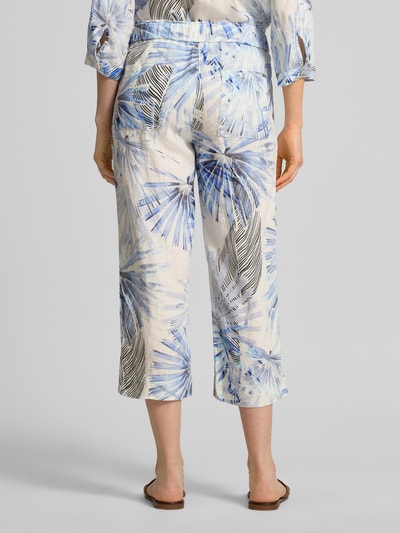 Frauenmodel trägt Wide Leg Caprihose im Allover-Look Modell 'PIA' von TONI aus reinem Leinen, elastischer Bund, blaue Muster, Ganzkörperansicht Rückansicht.
