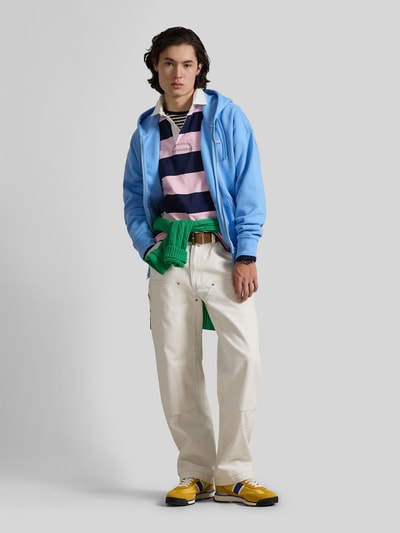 Männermodel trägt Relaxed Fit Sweatjacke aus Baumwoll-Mix von Polo Ralph Lauren in Hellblau, unifarben, mit Kapuze und Reißverschluss, Ganzkörperansicht von vorne.