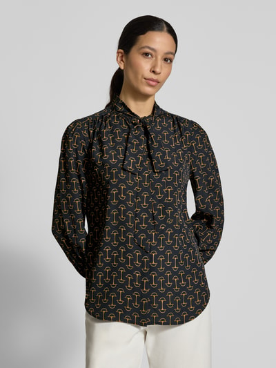 Frauenmodel trägt Regular Fit Langarmbluse mit Allover-Muster Modell 'KLARYCE' von Lauren Ralph Lauren in Schwarz mit gelben Formen, Stehkragen und Bindeschleife, Satintextur, Ganzkörperansicht von vorne.
