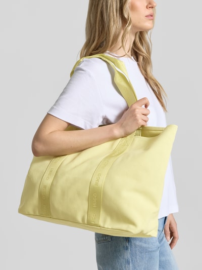 Frauenmodel trägt Strandtasche aus reiner Baumwolle Modell 'BECKY CA_TOTE' von HUGO, Optik: Unifarben, Label-Applikation, Tragehenkel, Detailaufnahme Schulterbereich.