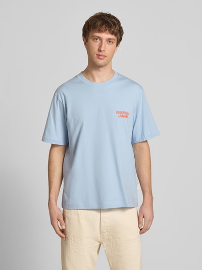 Männermodel trägt T-Shirt mit Label-Print von Jack & Jones, hellblau, Relaxed Fit, reine Baumwolle, Rundhalsausschnitt, Ganzkörperansicht von vorne.
