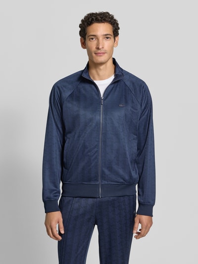 Männermodel trägt Regular Fit Sweatjacke mit Logo-Patch von Lacoste in Dunkelblau mit feiner Musterstruktur, Ganzkörperansicht von vorne. Herren Sweatjacke von Lacoste