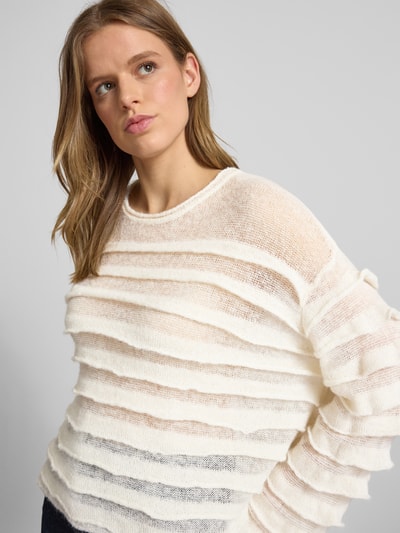 Frauenmodel trägt Strickpullover im Stufen-Look mit Rundhalsausschnitt von Gina Tricot, Material-Mix mit Alpaka-Anteil, Regular-Fit, Rückenlänge bei Größe S: 55 cm, Ärmellänge bei Größe S: 59 cm, helle Farbstruktur, transparente, weiche Textur, Nahaufnahme Oberkörper.