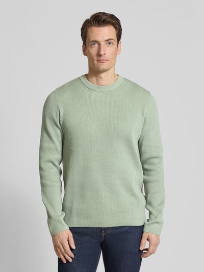 Männermodel trägt Relaxed Fit Strickpullover mit Rundhalsausschnitt von Lindbergh in grünlicher Ripp-Optik, Ganzkörperansicht von vorne.
