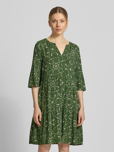 Kobiece model prezentuje Relaxed Fit Minikleid aus reiner Viskose od Christian Berg Woman Selection, zielony paisley, tunikowy dekolt, 3/4 rękaw, długość tyłu 89 cm, szerokość w rozmiarze 36: 49 cm, długość rękawa 39 cm, przód pełnej sylwetki.