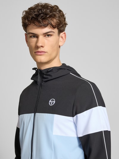 Męski model nosi Regular Fit Jacke mit Logo-Stitching Modell 'Caspio' od SERGIO TACCHINI, elastyczny materiał, kaptur z troczkiem, zamek, kieszenie, elastyczne mankiety; ujęcie: zbliżenie górnej części ciała z przodu.