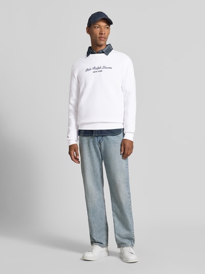 Mannenmodel draagt Regular Fit sweatshirt van katoenmix van Polo Ralph Lauren in wit met blauwe jeans, Ganzkörperansicht von vorne.