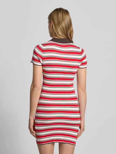 Frauenmodel trägt Polokleid aus Viskose-Mix mit kurzer Knopfleiste Modell 'Elenia' von LeGer by Lena Gercke, rot-weiß gestreift, Körpernaher-Schnitt, Minikleid, Polokragen, Rückansicht Ganzkörperansicht. Rückenlänge bei Größe 36: 83 cm, Brustweite bei Größe 36: 33 cm, Ärmellänge bei Größe 36: 19 cm.