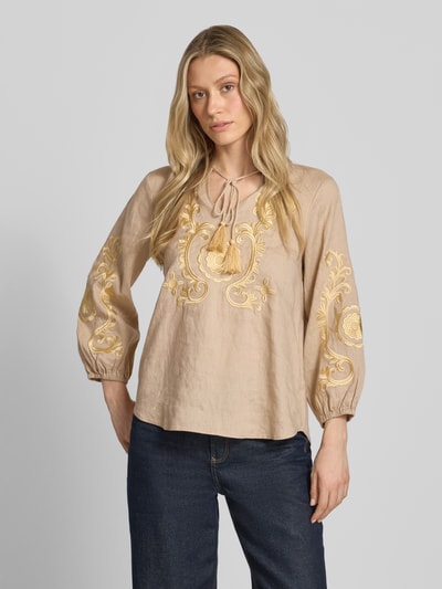 Frauenmodel trägt Leinenbluse mit Motiv-Stitching und Quasten-Details von Emily Van den Bergh in Beige mit gelben Stickereien, Loose-Fit, Tunikakragen, elastische Ärmelabschlüsse, Reines Leinen, Ganzkörperansicht von vorne.