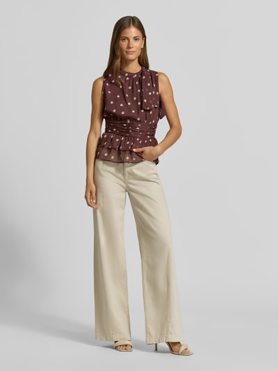 Vrouwenmodel draagt blouse met opstaande kraag, getailleerde pasvorm, Model 'Ansol' van Neo Noir, sierstrik, mouwloos design, met ruches, ruglengte bij maat 36: 54 cm, effen beige broek, tinten bruin en beige, structuur glad, contrast zachte top en wijde broek, volledige lichaamsweergave van voren.