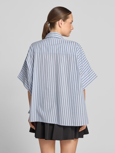 Frauenmodel trägt Oversized Kurzarmbluse aus reiner Baumwolle Modell 'JONKOE' von Essentiel Antwerp mit feinen Streifen, Ganzkörperansicht Rückansicht.