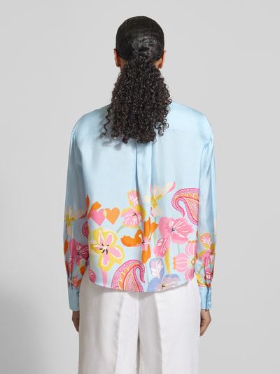 Vrouwenmodel draagt 'Boxy Fit Bluse aus Seide im Allover-Look' van HERZENS, zijde, boxy fit, alloverprint, rugaanzicht, ruglengte 58 cm, mouwlengte 60 cm, hemdkraag, knopenlijst. Ganzkörperansicht Rückansicht.