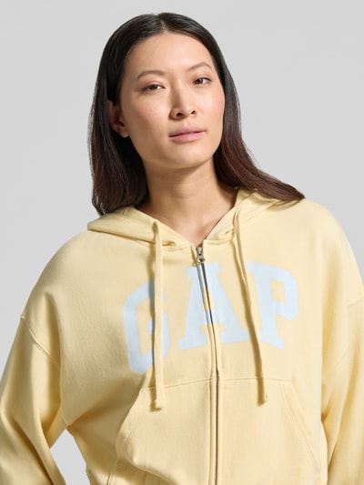 Vrouwenmodel draagt Regular Fit sweatjack met logo-stitching model 'Heritage' van GAP, katoenmix, capuchon, kangoeroezak, elastische boorden. Nahaufnahme Oberkörper.
