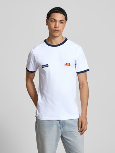 Męski model nosi T-Shirt mit Logo- und Label-Patch Modell 'RINGETTO' od Ellesse, biała bawełna, krój regular fit, okrągły dekolt, przód, zdjęcie całej sylwetki z przodu