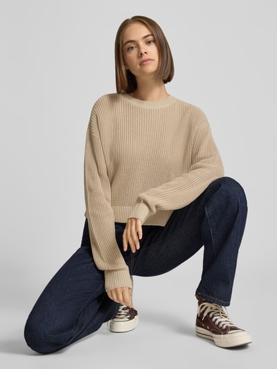 Kobieta prezentuje Relaxed Fit Pullover aus Baumwoll-Mix Modell 'Maysa' von NOISY MAY®, beżowy sweter o fakturze dzianiny, okrągły dekolt, długość tyłu w rozmiarze S: 50 cm, długość rękawa w rozmiarze S: 59 cm, Ganzkörperansicht von vorne.