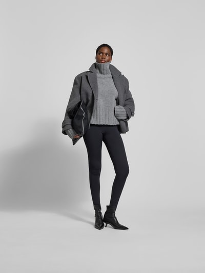 Frauenmodel trägt Oversized Pullover aus reiner Wolle von black palms in Grau mit gerippten Abschlüssen, Rollkragen, Rückenlänge 56 cm, Ganzkörperansicht von vorne.
