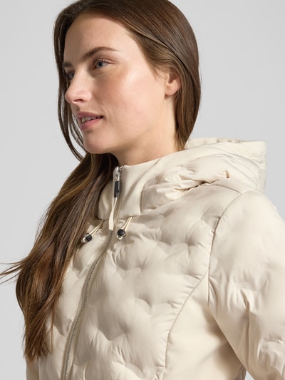 Frauenmodel trägt Regular Fit Steppjacke mit Kapuze von s.Oliver RED LABEL in Beige, unifarbene Optik, Nahaufnahme Oberkörper.