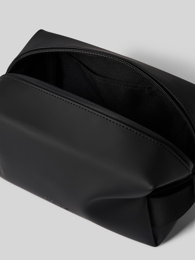 Produktfoto, Wash Bag mit Logo-Detail von Rains in Schwarz, glatte Oberfläche, Hauptfach mit Reißverschluss, Steckfach innen, Trageriemen, 20x14x11 cm, Länge Schulterriemen 14 cm.