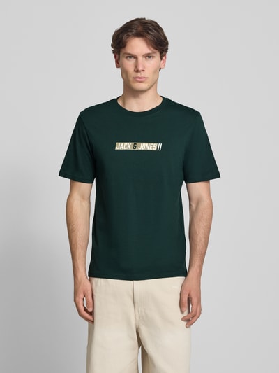 Männermodel trägt Regular Fit T-shirt met logoprint model 'Munk' van JACK & JONES, puur katoen, ruglengte maat M 74 cm, Ganzkörperansicht van voren.