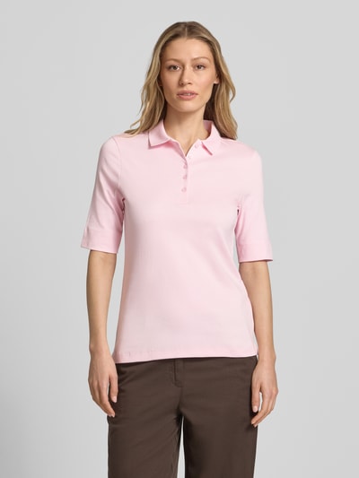 Modelka nosi Slim Fit Poloshirt mit Knopfleiste und 1/2-Arm von Christian Berg Woman, bawełna, krój slim fit, listwa guzikowa, rękaw o dł. 1/2, długość tyłu w rozmiarze 36: 61 cm, jasnoróżowy, gładka faktura, widok całej sylwetki z przodu