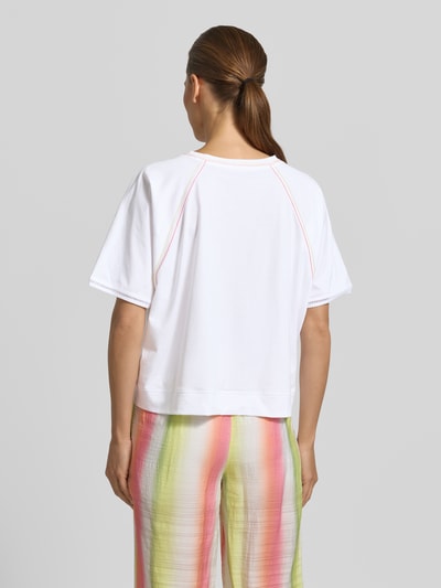 Modelka nosi Relaxed Fit T-Shirt mit Rundhalsausschnitt von Marc Cain, damski t-shirt z bawełny, ozdobne szwy, długość tyłu 52 cm, widok całej sylwetki z tyłu.