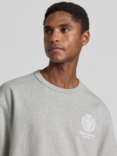 Mannenmodel draagt Relaxed Fit T-shirt uit puur katoen van Polo Ralph Lauren in lichtgrijs, zachte textuur, detailopname bovenlichaam.