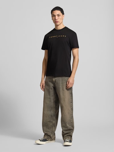 Männermodel trägt Regular Fit T-Shirt aus reiner Baumwolle von Tommy Jeans, Optik: Unifarben, Label-Stitching-Applikation, Ganzkörperansicht von vorne.