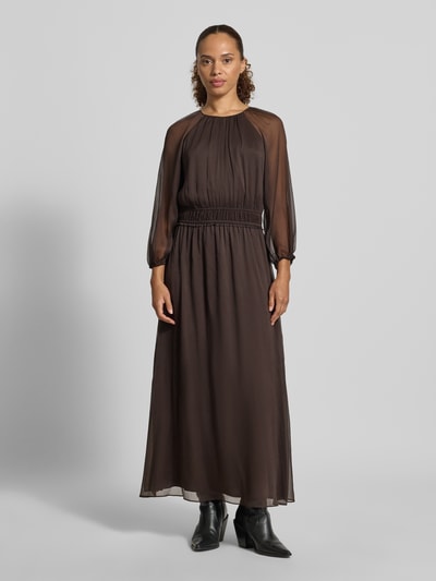 Vrouwenmodel draagt maxi-jurk in semi-transparant design van comma, getailleerd met ronde hals, plooien, met lange mouwen, Ganzkörperansicht von vorne. Ruglengte bij maat 36: 132 cm, borstwijdte bij maat 36: 45 cm, mouwlengte bij maat 36: 49 cm.