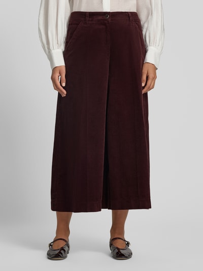 Frauenmodel trägt weite, bordeauxrote Cordhose mit feiner Struktur und Bügelfalte, Weite Hose aus reiner Baumwolle Modell 'MELLI S' von Brax, Damen Weite Hose, Ganzkörperansicht von vorne.
