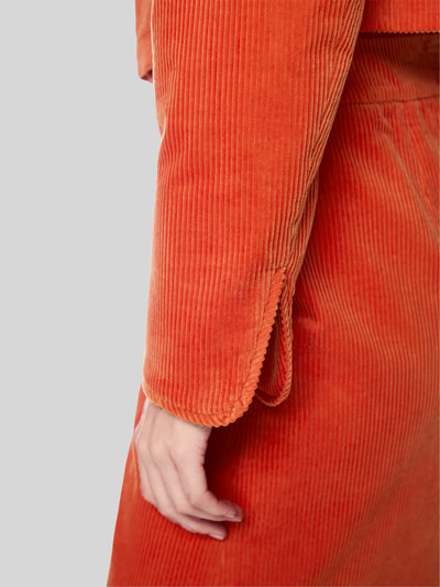 Frauenmodel trägt Regular Fit Blazer aus Cord mit Rundhalsausschnitt von Marc Cain, orange, Rippenstruktur, reine Baumwolle, Detailaufnahme, Nahaufnahme Ärmel und Hand, Damen Blazer Kontext.