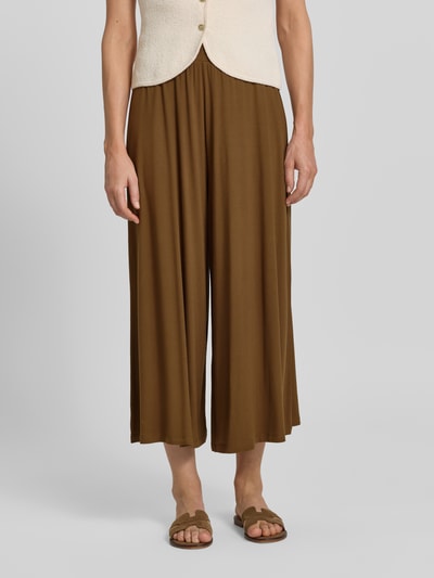 Frauenmodel trägt Wide Leg Culotte aus Viskose-Mix von Armedangels in Braun, lockere Passform, glatte Textur, Nahaufnahme Oberkörper. Damen Culotte von Armedangels.