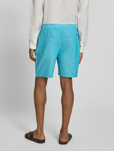 Männermodel trägt Shorts mit elastischem Bund von Scotch & Soda im Baumwoll-Leinen-Mix, türkis, Regular Fit, Ganzkörperansicht Rückansicht.
