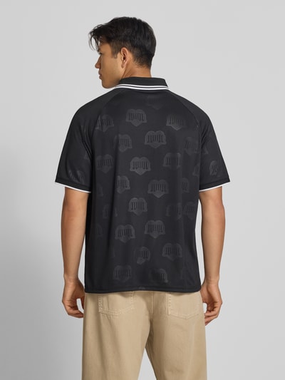 Männermodel trägt schwarzes Funktionsshirt mit dezentem Logo-Muster und weißem Kragen von Adidas, Modell 'Terrace', Ganzkörperansicht Rückansicht, Herren Funktionsshirt Regular Fit, Rückenlänge bei Größe M 71 cm.