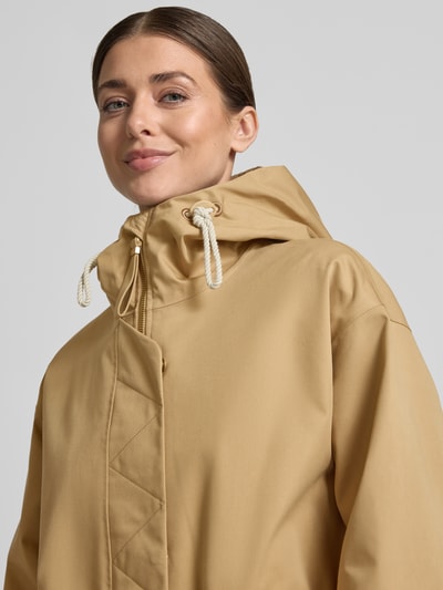 Modelka kobieca ma na sobie Regular Fit Mantel mit durchgängiger Abdeckleiste Modell 'Tory' od G-LAB z mieszanki bawełny, kolor beżowy, kaptur z tunelem, stójka, zamek, kieszenie, elastyczne mankiety, długość tyłu w rozmiarze S: 96 cm, szerokość ramion w rozmiarze S: 49 cm, szerokość klatki piersiowej w rozmiarze S: 54 cm, długość rękawa w rozmiarze S: 53 cm; tekstura gładka; zbliżenie na górną część ciała.