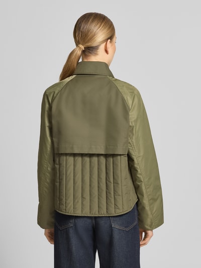 Vrouwenmodel draagt Trenchcoat met Eingrifftaschen model 'Zyla Neola' van MOS MOSH, olijfgroen, katoenmix, regular fit, knoopsluiting, steekzakken, ruglengte 60 cm, schouderbreedte 43 cm, borstwijdte 51 cm, mouwlengte 61 cm, volledig zicht van achteren.