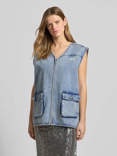 Frauenmodel trägt Jeansweste mit Label-Patch von Karo Kauer, Reine Baumwolle, Loose-Fit, V-Ausschnitt, Reißverschluss, Pattentaschen mit Knopfverschluss, Rückenlänge 71 cm, Schulterbreite 48 cm, Brustweite 65 cm, mittleres Blau, Nahaufnahme Oberkörper.