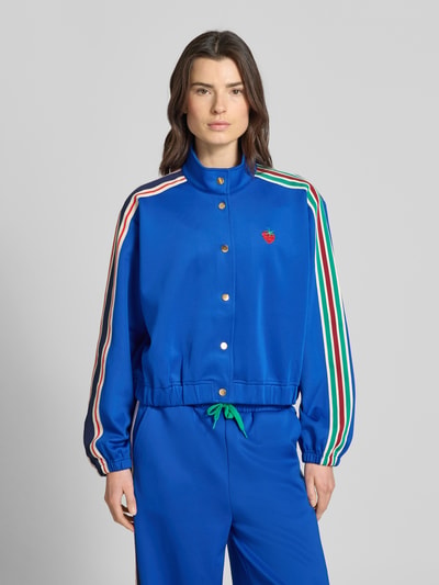 Frauenmodel trägt blaue Sweatjacke mit Kontraststreifen, Stehkragen und Knopfleiste, Modell 'Brooklynn' von Lollys Laundry, Relaxed-Fit, Material-Mix mit Stretch-Anteil, Ganzkörperansicht von vorne.