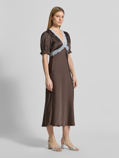 Modelka prezentuje sukienkę midi Regular Fit Midikleid mit Spitzenbesatz Modell 'Vipe' od Neo Noir, elastyczna mieszanka materiałów, obszycie koronką, dekolt w serek, zakończenia rękawów z falbanami, długość tyłu w rozmiarze 36: 120 cm, szerokość w rozmiarze 36: 49 cm, długość rękawów w rozmiarze 36: 32 cm, kolor brązowy z niebieską koronką, gładka tekstura, krój regular fit, z krótkim rękawem, Ganzkörperansicht z przodu.