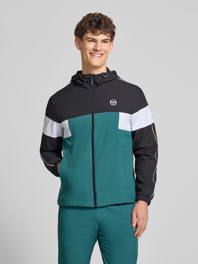 Männermodel trägt Regular Fit Jacke mit Logo-Stitching Modell 'Caspio' von SERGIO TACCHINI in Schwarz, Weiß und Grün, Reißverschluss, Kapuze, Eingrifftaschen, elastischer Material-Mix, Ganzkörperansicht von vorne.
