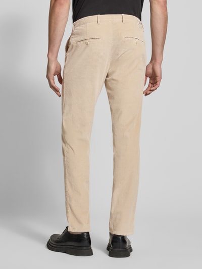 Männermodel trägt beigefarbene Modern Fit Cordhose aus Baumwoll-Mix Modell 'Fabio' von Brax, strukturierte Oberfläche, Ganzkörperansicht Rückansicht.
