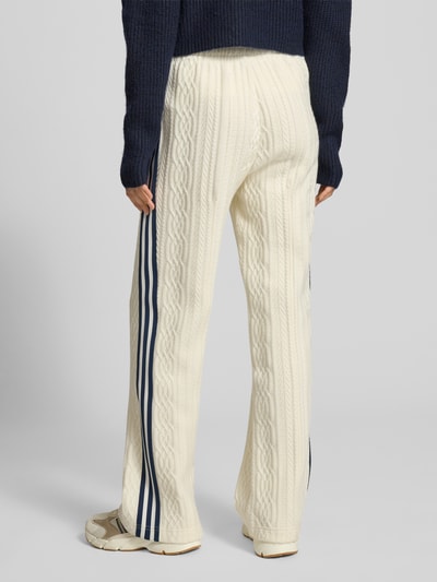 Vrouwenmodel draagt Loose Fit Strickhose uit viscosemix van adidas Originals met galonstrepen, gestikt logo, gebroken wit, volledig achteraanzicht.
